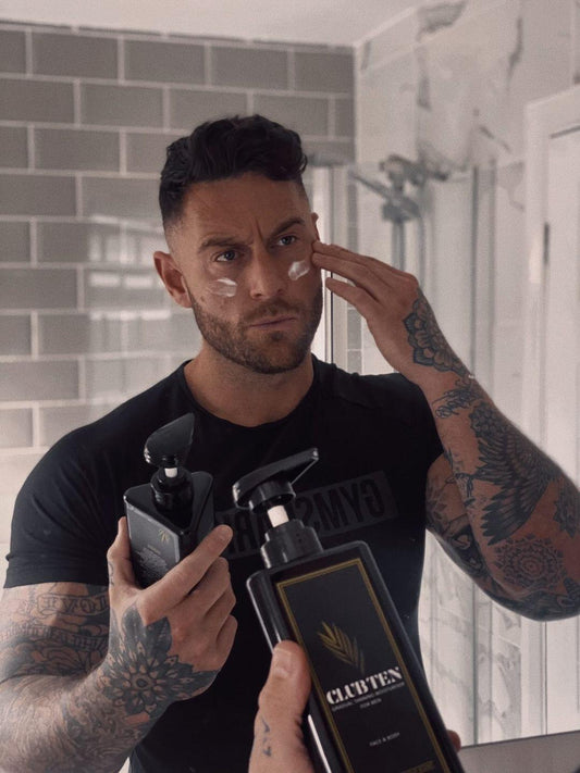 A man with tattoos and a tan using club ten on his face