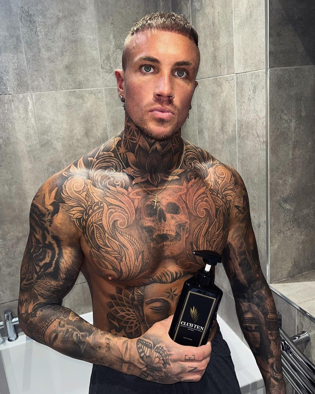 A  well groomed Man with tattoos using gradual tan moisturiser on his body. He has a naturally, gradually developed tan. 